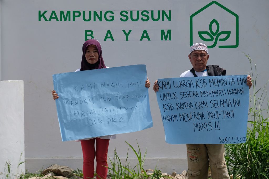 Warga membawa poster tuntutan di depan tulisan Kampung Susun Bayam, Jakarta Utara, Senin (21/11/2022). 