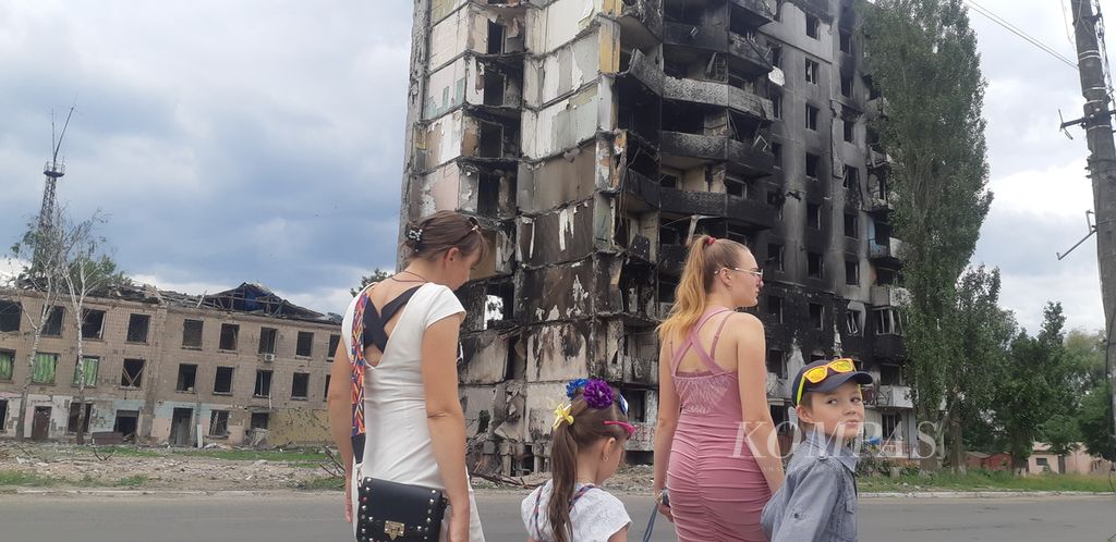 Warga berjalan melintasi dekat salah satu rumah susun yang hancur di Borodyanka, Provinsi Kyiv, pada Jumat (17/6/2022). Distrik itu salah satu kawasan yang dikuasai Rusia selama beberapa pekan awal perang Rusia-Ukraina meletus.