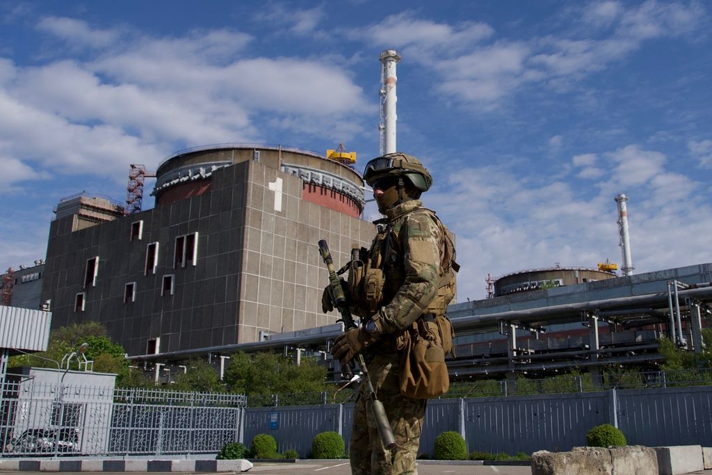 Seorang tentara Rusia berpatroli di wilayah PLTN Zaporizhia di Enerhodar, 1 Mei 2022. Ukraina dan Rusia saling lempar tuduhan soal dalang serangan atas fasilitas nuklir terbesar di Eropa tersebut.  