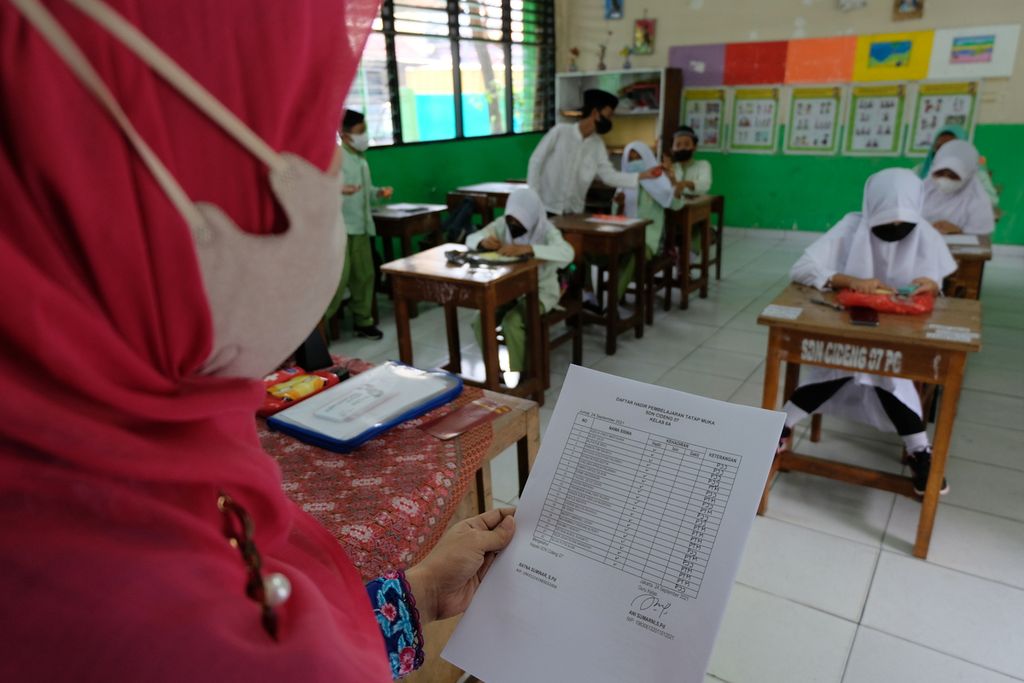 Seorang guru SDN 07 Cideng, Jakarta, menunjukkan daftar presensi siswa di kelasnya, Jumat (24/9/2021). SDN 07 Cideng merupakan salah satu sekolah yang menggelar pembelajaran tatap muka (PTM) terbatas di Jakarta. Pembelajaran luring berlangsung tiga kali dalam seminggu dan diikuti hanya 50 persen siswa, sementara sebagian lainnya belajar dari rumah.