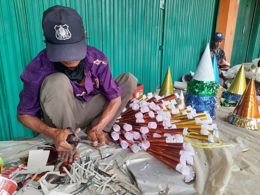 Rojali (50) dan Korsan (60) membuat trompet tahun baru dari kertas di kawasan Kota Tua, Jakarta, Sabtu (31/12/2022). Keduanya merupakan pedagang musiman dari Cikarang, Jawa Barat.