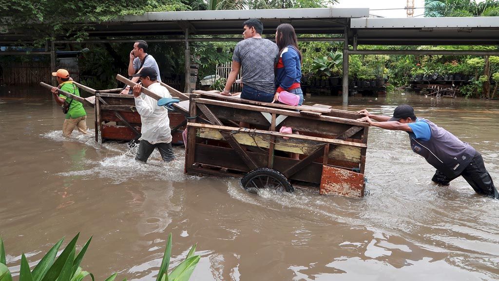 Dua penarik gerobak mengantarkan penumpang melintasi banjir di Jalan Letjen Suprapto, Jakarta Pusat, Selasa (21/2). Banjir di jalur lambat jalan menuju Pasar Senen ini terjadi setelah hujan lebat turun kemarin.