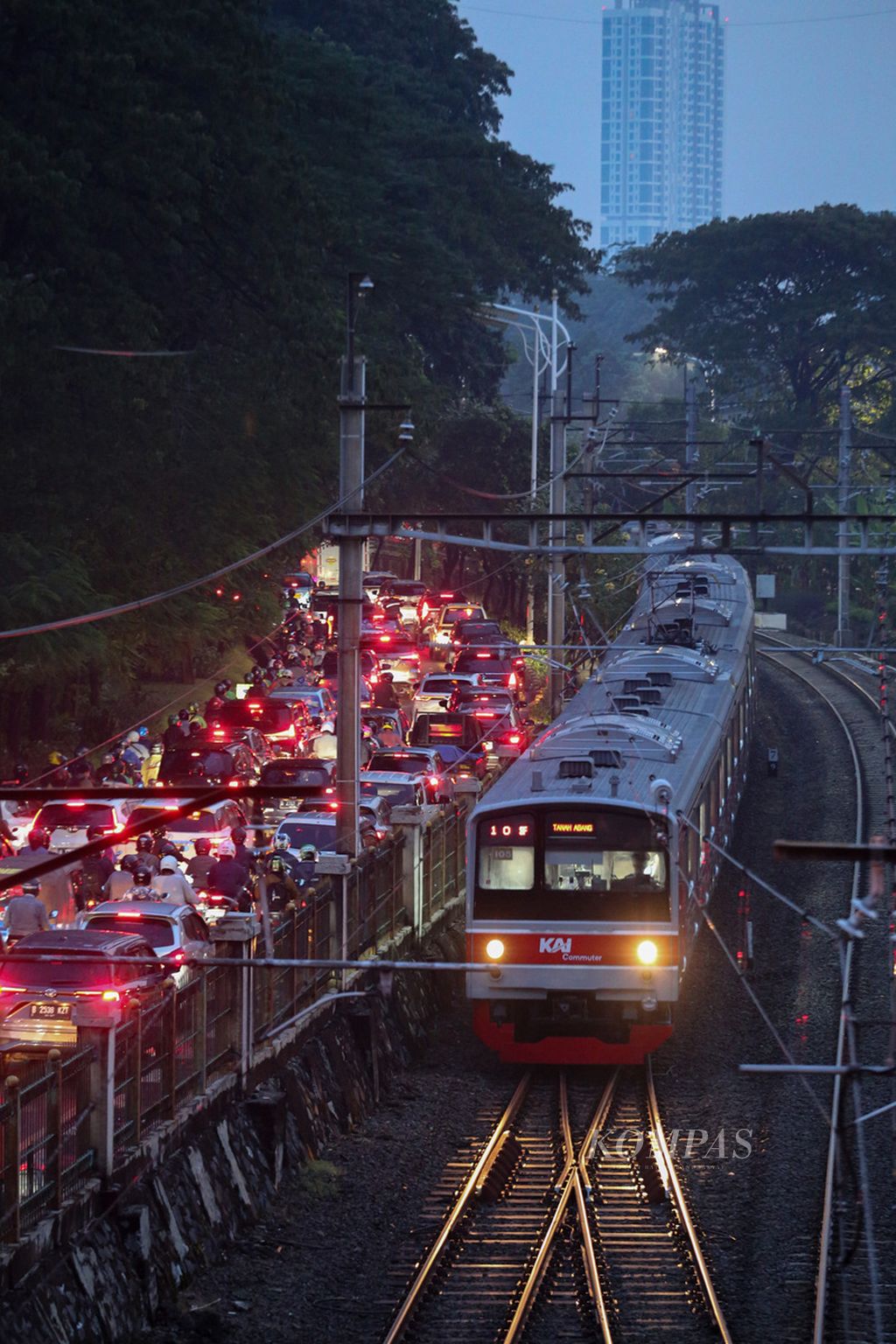 Kereta komuter melintas di samping kendaraan yang terjebak macet di Jalan Pejompongan Raya, Jakarta, saat jam pulang kerja, Selasa (11/6/2024). Transportasi publik dapat menjadi salah satu solusi untuk mengurangi kemacetan di Jakarta. Setiap harinya, sekitar 24 juta kendaraan berada di wilayah DKI Jakarta.