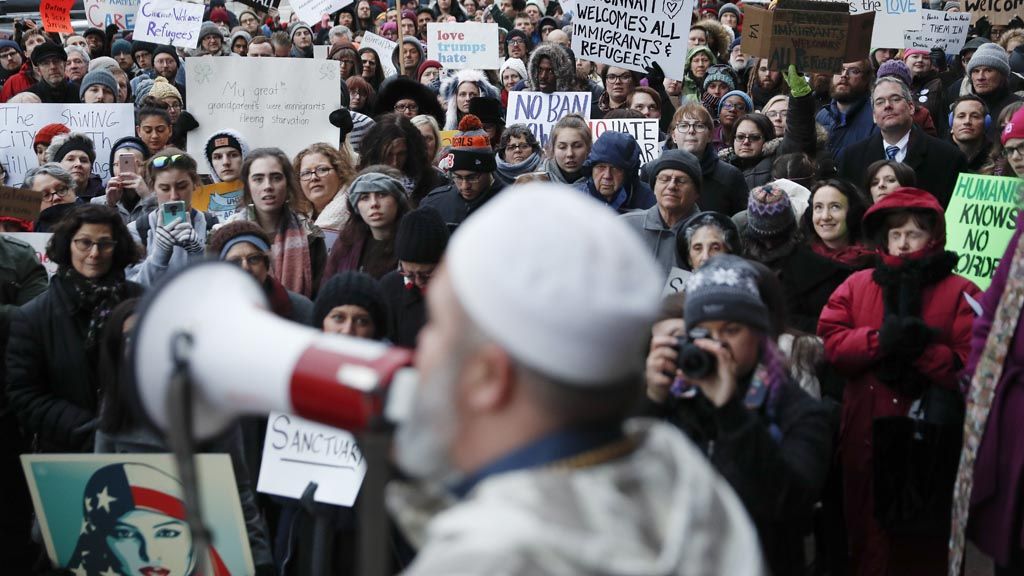 Pengunjuk rasa berkumpul menentang kebijakan Presiden Donald Trump mengenai larangan kedatangan warga dari tujuh negara berpenduduk mayoritas Muslim dan membatalkan kedatangan pengungsi Suriah, Senin (30/1/2017) di luar balai kota di Cincinnati. 