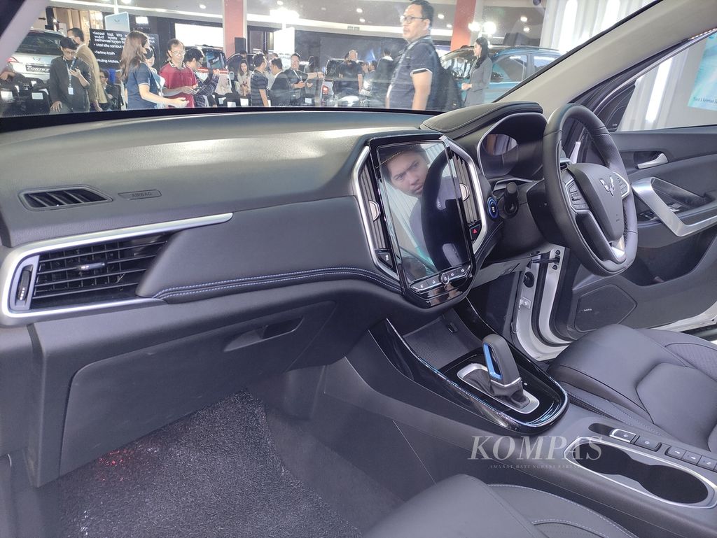 Pengunjung yang tengah mengamati Wuling New Almaz RS Pro Hybrid terefleksikan di layar utama mobil tersebut seusai diluncurkan di Jakarta, Kamis (5/10/2023).