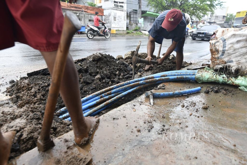 Buruh lepas penggali tanah menyelesaikan proyek penggantian kabel fiber optik di kawasan Kedoya Utara, Jakarta Barat, Kamis (23/12/2021).  