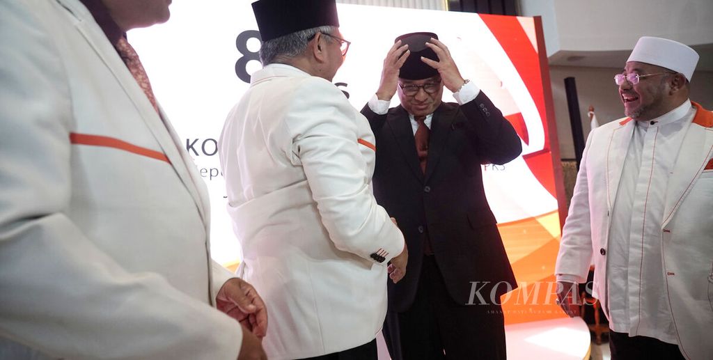 Anies Baswedan mengenakan songkok yang diberikan Presiden PKS Ahmad Syaikhu (kiri) dan Sekjen PKS Aboe Bakar Alhabsyi (kanan), di Kantor DPP Partai Keadilan Sejahtera (PKS), Jakarta, Kamis (23/2/2023). 
