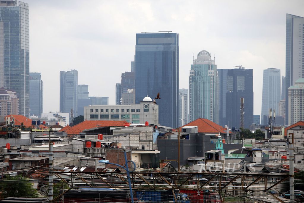 Perkampungan padat penduduk dengan latar belakang gedung bertingkat di Jakarta, Jumat (23/12/2022).