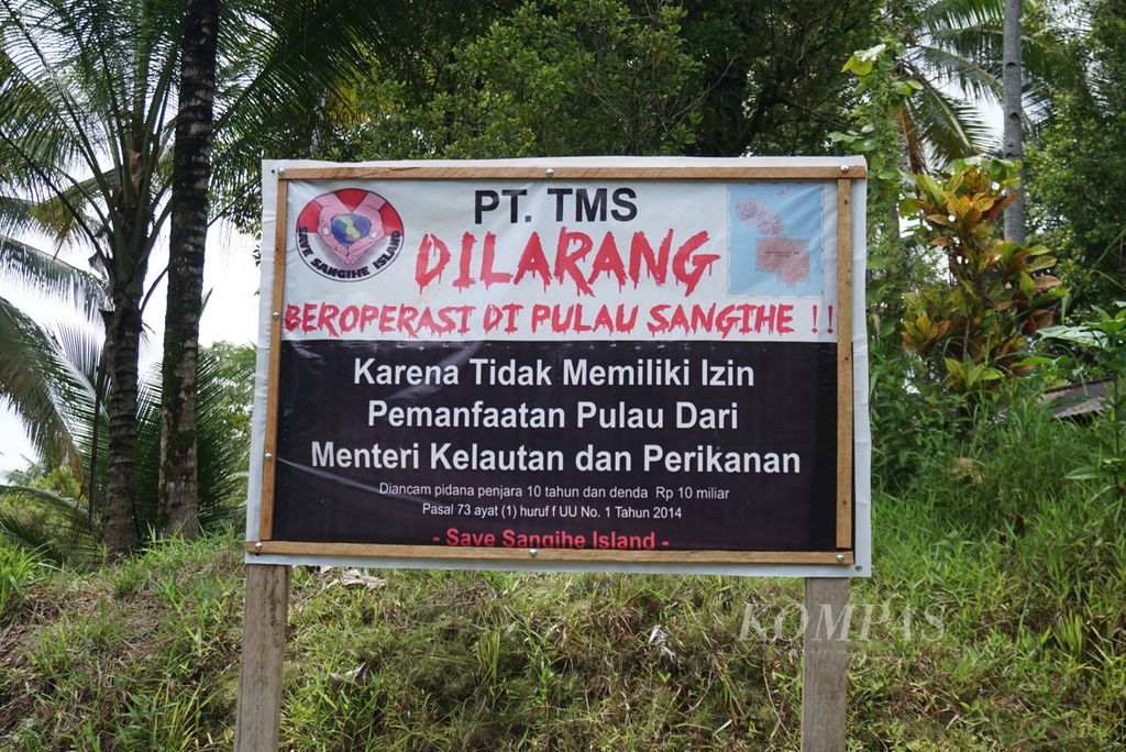 Sebuah spanduk penolakan terhadap PT Tambang Mas Sangihe berdiri di jalan lintas kecamatan wilayah Tabukan Selatan Tengah, Kepulauan Sangihe, Sulawesi Utara, Sabtu (7/8/2021). Spanduk itu dipasang di sejumlah tempat oleh gerakan Save Sangihe Island.