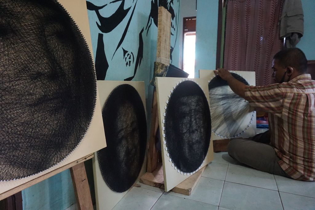 Surip (45), pegiat <i>string art</i>, sedang mengerjakan karya seni dari benang dan paku di rumahnya di Desa Haduyang, Kecamatan Natar, Kabupaten Lampung Selatan, Lampung. Minggu (14/3/2021).