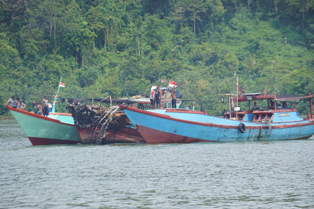 Sebuah bangkai kapal ditarik di sekitar Dermaga Wijayapura, Cilacap, Jawa Tengah, Rabu (4/5/2022) pagi. Total ada 45 kapal yang terbakar sejak Selasa sore dan kerugian material mencapai Rp 130 miliar.