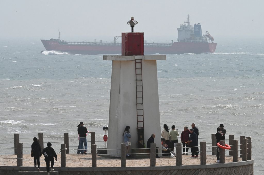 Sebuah kapal berlayar di Selat Taiwan, melewati turis di mercusuar di Pulau Pingtan, titik terdekat ke Taiwan, di Provinsi Fujian, tenggara China, pada 8 April 2023. 