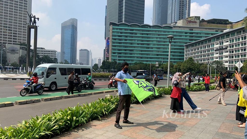 Warga penggemar MotoGP berfoto dengan latar belakang Patung Selamat Datang sembari menanti kedatangan para pebalap MotoGP dalam Parade MotoGP di Jakarta, Rabu (16/3/2022). Warga berkumpul di kawasan pedestrian untuk menyaksikan para pebalap melintas