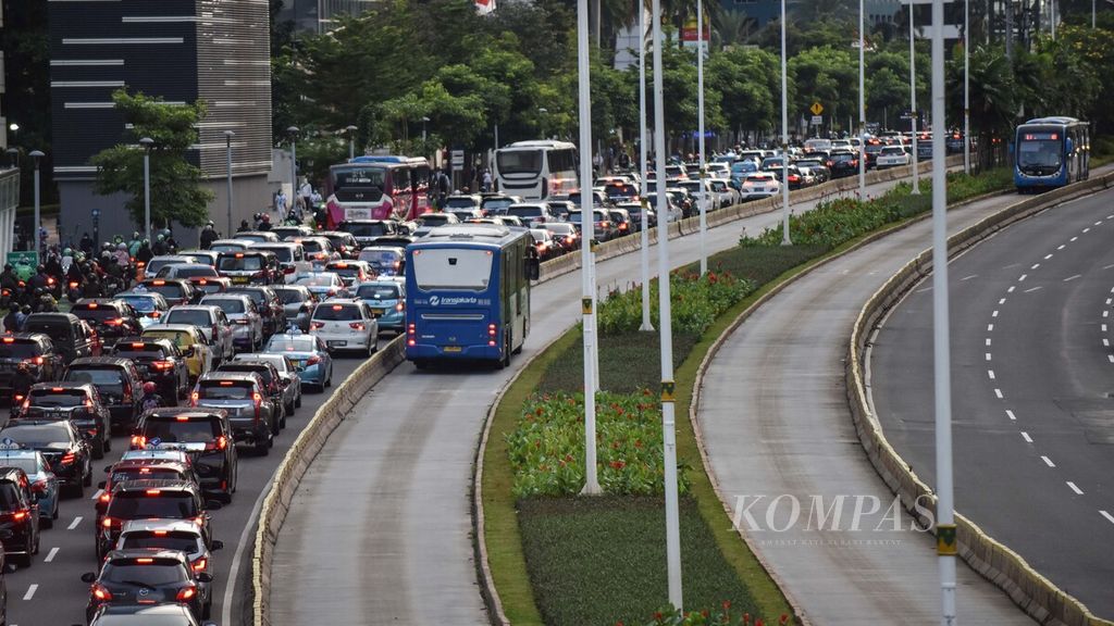 Bus Transjakarta melintasi kendaraan yang terjebak kemacetan di Jalan Jenderal Sudirman, Jakarta, Senin (13/12/2021).