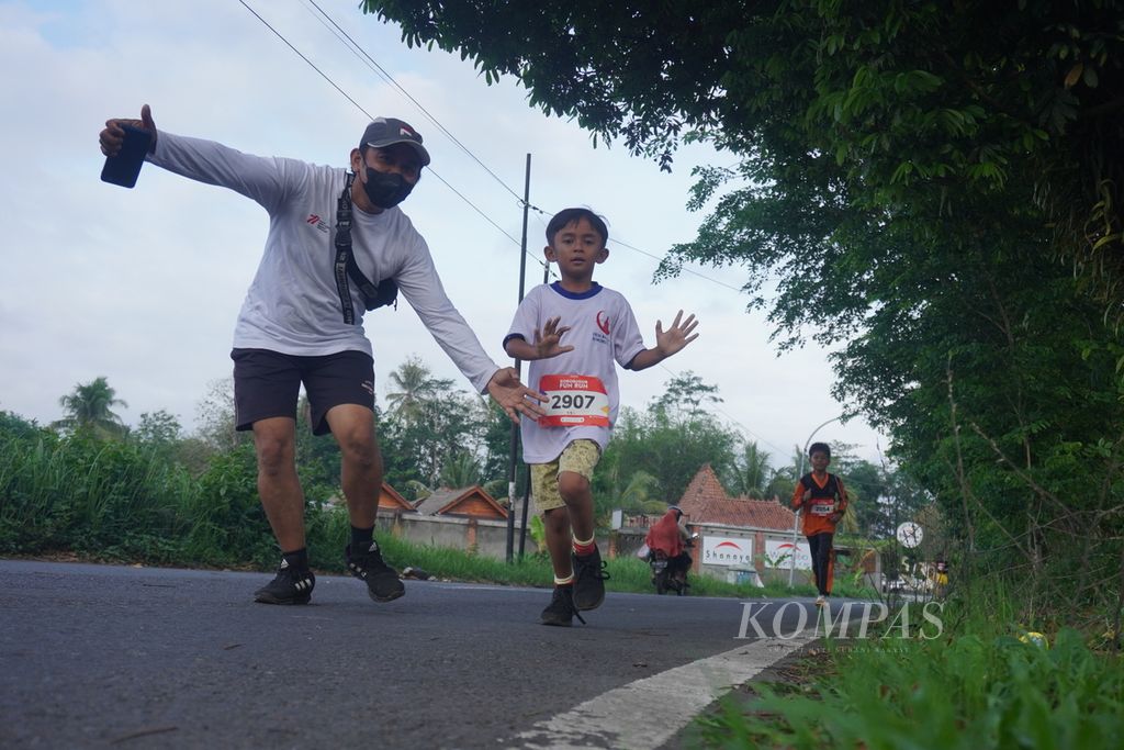 Ayah dan anak peserta Borobudur Fun Run berpose saat berlari melintasi perkampungan di Desa Borobudur, Kecamatan Borobudur, Kabupaten Magelang, Jawa Tengah, Sabtu (3/12/2023). 