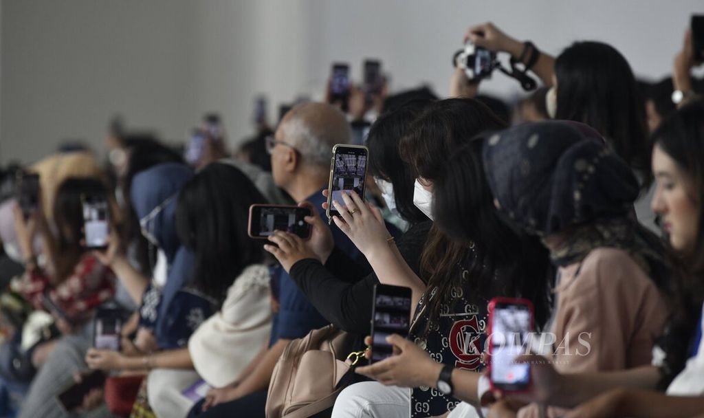 Tamu undangan sibuk mengabadikan momen peragaan busana menggunakan gawai dalam Jakarta Fashion Week yang menampilkan persenbahan Pinterest dengan tema The Nexus of Modest Wear di City Hall Pondok Indah Mall 3, Jakarta, Jumat (28/10/2022). 
