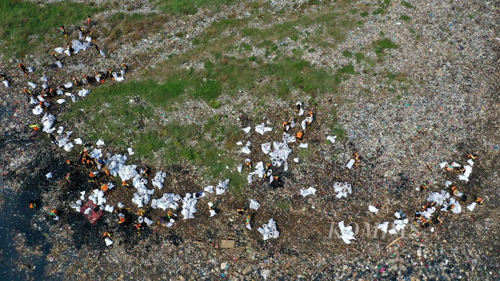 Foto udara petugas gabungan Dinas Lingkungan Hidup DKI Jakarta membersihkan sampah yang menumpuk di hutan mangrove Muara Angke, Penjaringan, Jakarta Utara, Kamis (13/7/2023).