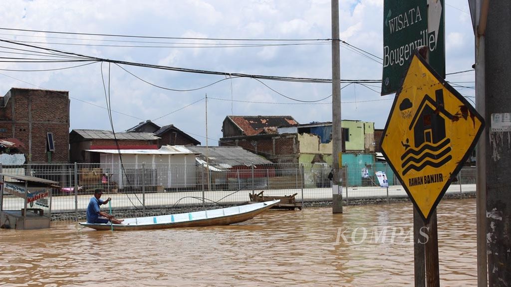 Warga menggunakan perahu melintasi Jalan Anggadireja, Baleendah, Kabupaten Bandung, Jawa Barat, yang tergenang banjir, awal 2019.