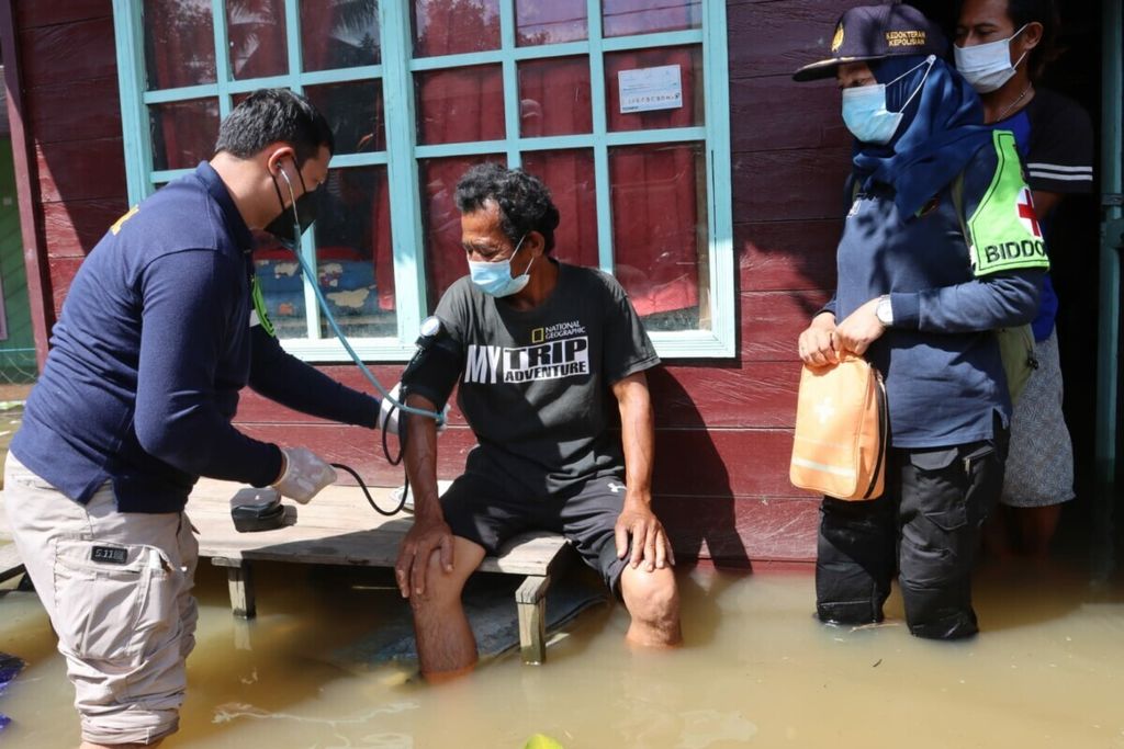 Di tengah banjir, seorang petugas kesehatan memeriksa salah satu warga terdampak banjir di Kabupaten Katingan, Kalteng, Senin (23/8/2021).