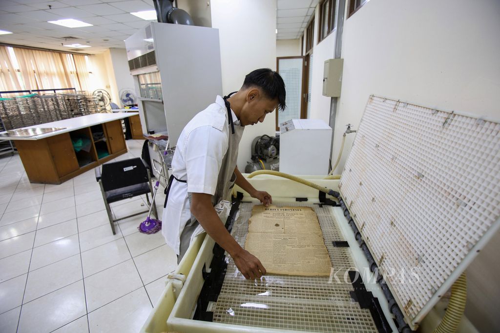 Konservator memasukkan surat kabar lama ke salah satu alat untuk <i>leafcasting </i>di Perpustakaan Nasional, Salemba, Jakarta, Senin (5/8/2024). Konservasi koleksi Perpustakaan Nasional menjadi upaya untuk merawat serta menjaga koleksi agar selalu dalam keadaan baik. Koleksi yang dikonservasi beragam mulai dari naskah kuno, surat kabar lama, majalah, hingga peta. 