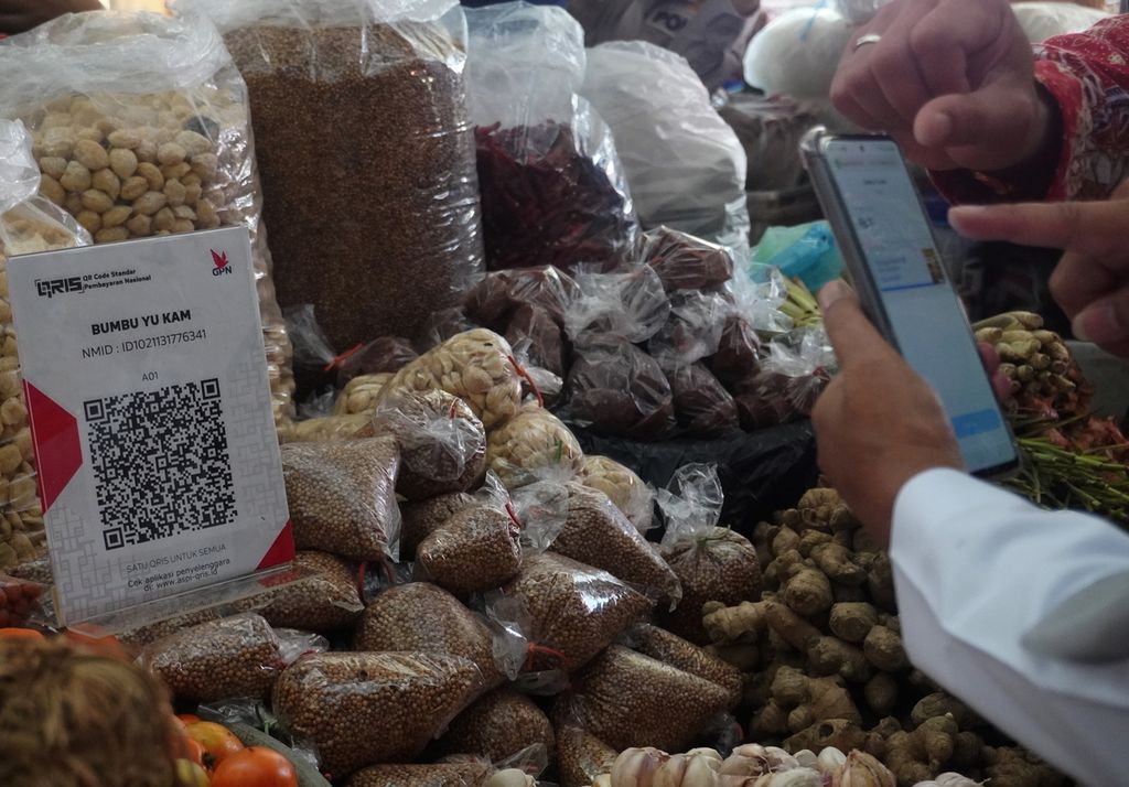  Bupati Tegal Umi Azizah (kanan) bertransaksi menggunakan kode pindai cepat standar Indonesia atau QRIS di Pasar Lebaksiu, Kabupaten Tegal, Jawa Tengah, Rabu (8/12/2021). Pedagang di pasar tradisional mulai marak menerapkan pembayaran menggunakan QRIS. 