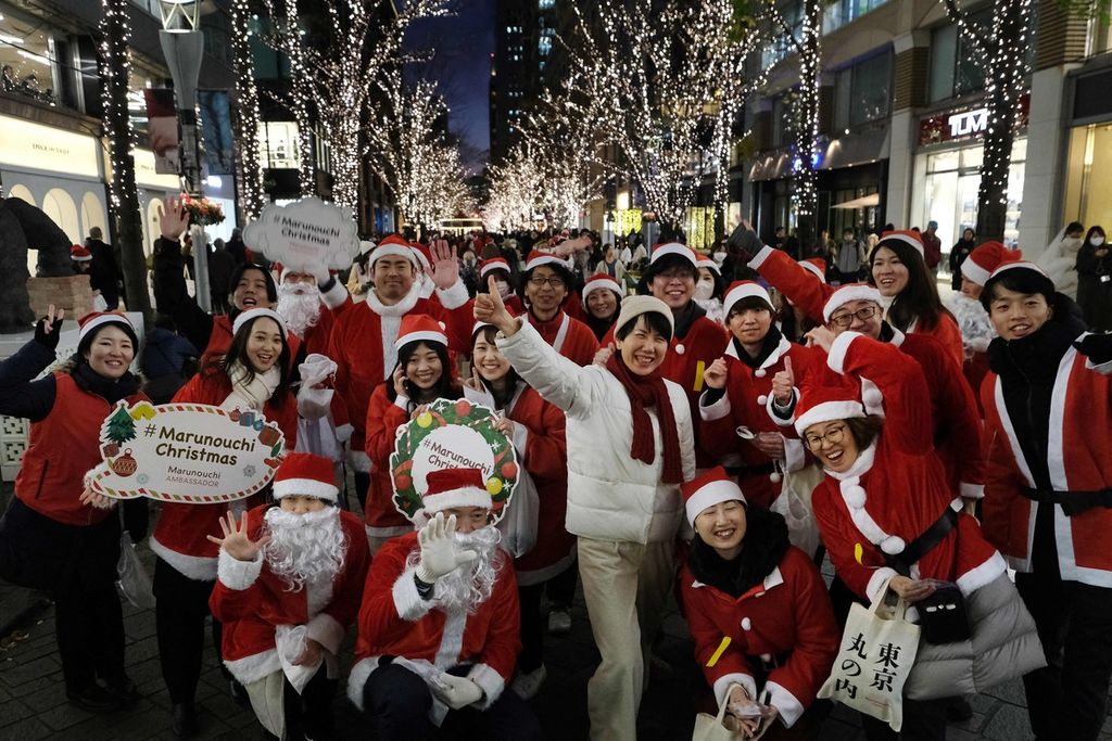 Para pekerja memakai kostum ala Sinterklas saat Sinterklas menyambut seorang pengunjung dalam parade Natal di kawasan pusat bisnis Marunouchi di Tokyo, Jepang, 22 Desember 2023. 