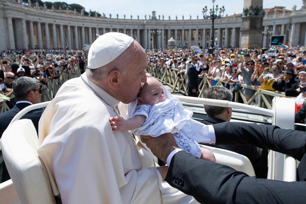 Foto yang diambil Media Vatikan per 15 Mei 2022 ini menunjukkan Paus Fransiskus sedang mencium kening seorang bayi di mobil paus pada misa kanonisasi di Lapangan Santo Petrus di Vatican. 