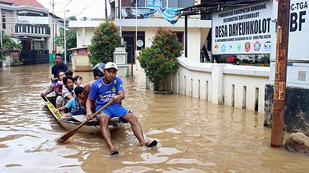 Warga menggunakan perahu untuk melintasi jalanan yang terendam banjir di Desa Dayeuhkolot, Kabupaten Bandung, Jawa Barat, Sabtu (25/1/2020). Banjir melanda empat kecamatan di Kabupaten Bandung sejak Kamis malam.