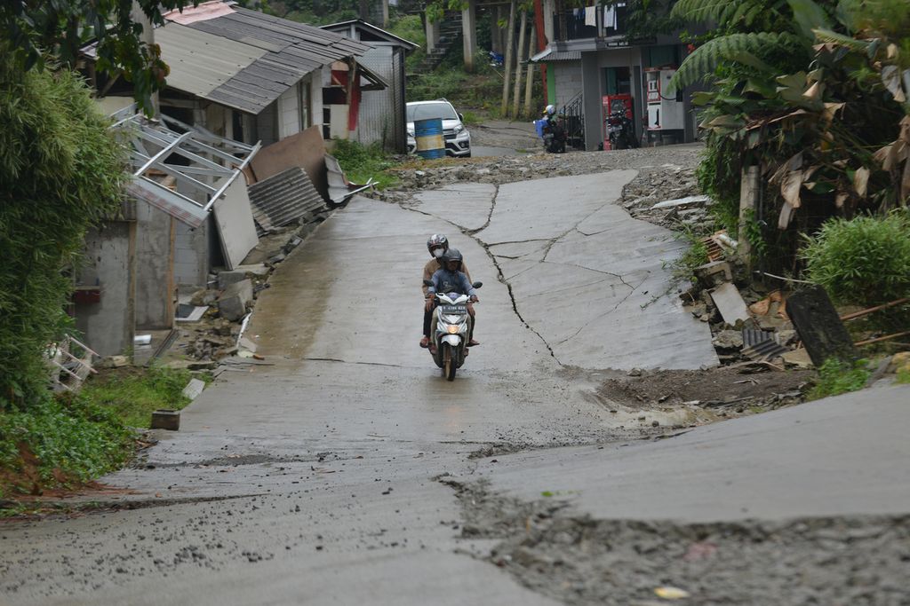Pengendara sepeda motor melintasi ruas jalan yang rusak akibat pergerakan tanah di Kampung Curug, Desa Bojong Koneng, Kecamatan Babakan Madang, Kabupaten Bogor, Rabu (9/11/2022). 