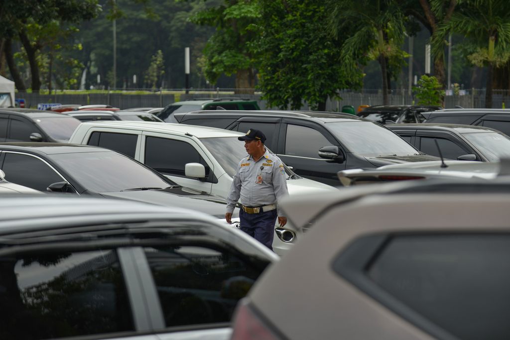 Petugas Dinas Perhubungan (Dishub) DKI Jakarta berjalan di antara mobil yang terparkir di lapangan parkir Ikatan Restoran dan Taman Indonesia (IRTI) Monas, Jakarta Pusat, Selasa (7/10/2023).