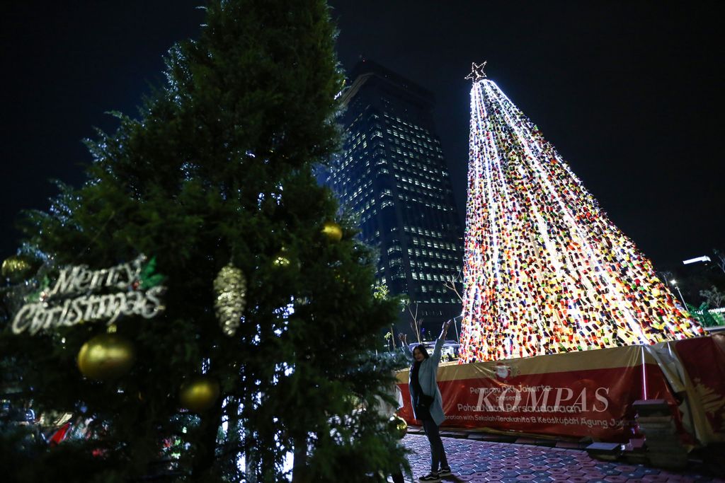 Warga berfoto dengan latar belakang pohon Natal Persaudaraan di pusat kuliner baru Thamrin 10 di Jalan Protokol MH Thamrin, Jakarta Pusat, Senin (23/12/2019) malam. 