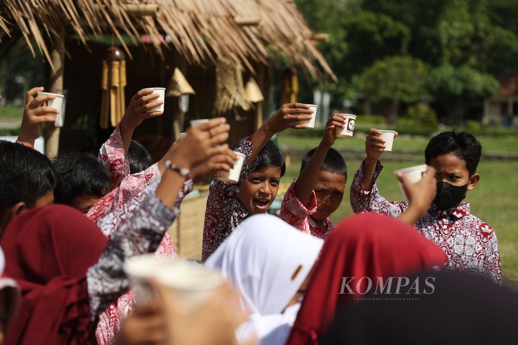 Murid SD menerima minuman jamu yang dibagikan dalam acara Festival Sewu Bakul Jamu di kompleks Candi Banyunibo, Desa Bokoharjo, Kecamatan Prambanan, Kabupaten Sleman, Daerah Istimewa Yogyakarta, Selasa (19/12/2023). 