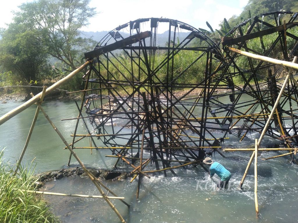 Odo Hadori memeriksa kelayakan kincir air yang dibuat dari bambu dan kayu, Rabu (13/9/2023). Air dari kincir digunakan mengairi sawah tadah hujan.