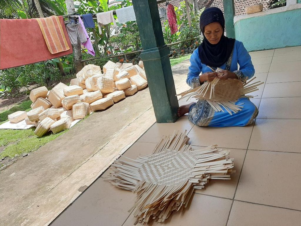 Seorang ibu terlihat menganyam besek di teras rumahnya di Desa Wadas, Kecamatan Bener, Kabupaten Purworejo, Rabu (16/2/2022). Bahan baku bambu yang digunakan untuk besek adalah bambu yang diambil dari lahan yang akan dijadikan sebagai lokasi penambangan.
