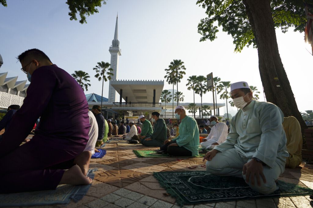 Umat Muslim Malaysia mengenakan masker pelindung saat berdoa di luar Masjid Nasional bertepatan dengan Idul Fitri, di Kuala Lumpur, Malaysia, Kamis, 13 Mei 2021.