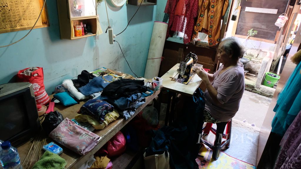 Dora (64), transpuan asal Jawa Timur, sedang menjahit di rumahnya di kawasan padat penduduk di Jatinegara, Jakarta Timur (19/7/2022). Ia merantau ke Jakarta sejak 30 tahun lalu, kemudian bertahan hidup dengan mengamen, bekerja serabutan, hingga menjahit.