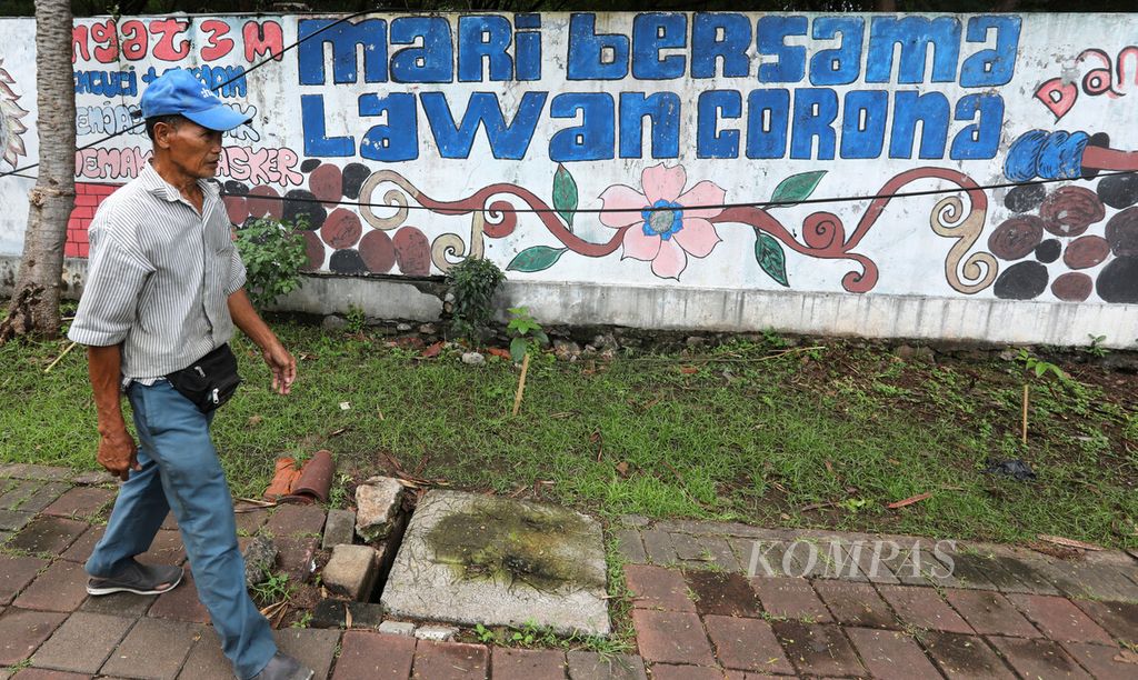 Warga melintas di depan mural tentang waspada Covid-19 di kawasan Senen, Jakarta Pusat, Kamis (9/2/2023). Situasi pandemi Covid-19 di Indonesia dinilai telah terkendali. Pemerintah menyiapkan beberapa langkah di masa peralihan status pandemi Covid-19 menjadi endemi pada 2023. 