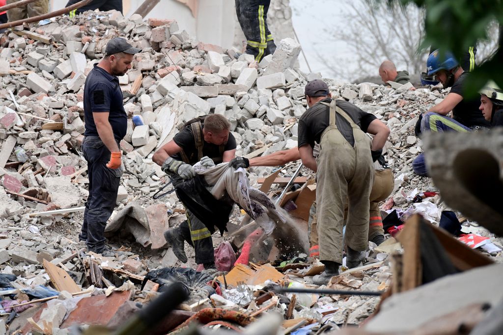 Petugas pemadam kebakaran dan tim penyelamat membersihkan puing-puing setelah sebuah gedung apartemen hancur sebagian akibat serangan rudal Rusia di Chasiv Yar, wilayah Ukraina timur, 10 Juli 2022. 