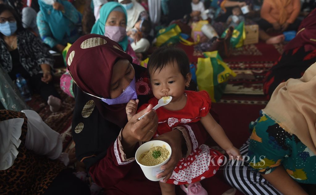 Ibu memberi makan bayinya dengan bubur sehat saat peluncuran Gebyar Lomba Balita Sehat di Halaman Balaikota Surabaya, Jawa Timur, Januari 2022. 
