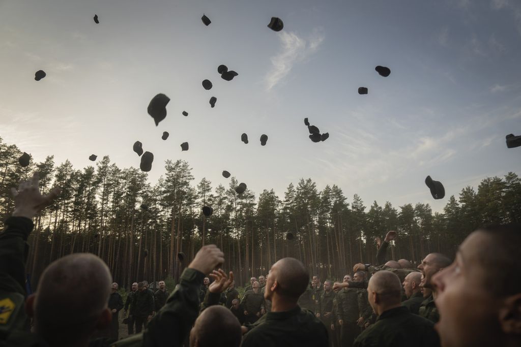 Tentara yang baru direkrut melemparkan topi mereka untuk merayakan akhir masa pelatihan di sebuah pangkalan militer dekat Kyiv, Ukraina, Senin (25/9/2023). 