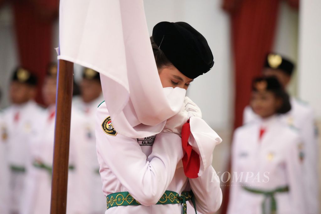 Perwakilan Paskibra, Kachina Ozora, mencium bendera merah putih saat Upacara Pengukuhan Paskibraka di Istana Negara, Selasa (15/8/2023). Presiden Joko Widodo mengukuhkan 76 Paskibraka dari 38 provinsi, termasuk empat provinsi baru, yang akan bertugas pada Upacara HUT ke-78 Kemerdekaan Indonesia. KOMPAS/HERU SRI KUMORO 15-08-2023