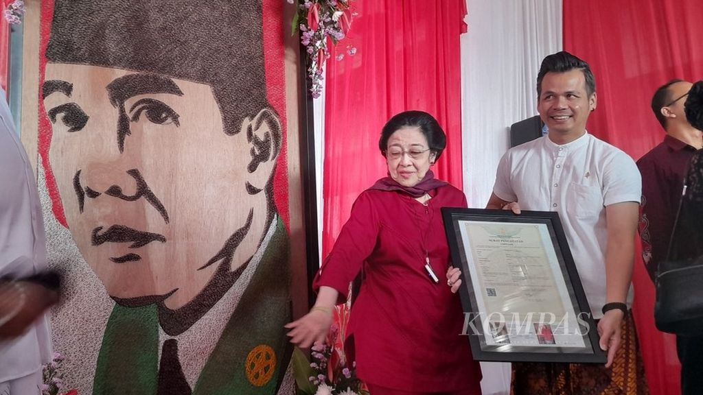 Ketua Umum PDI Perjuangan Megawati Soekarnoputri berada di sisi kanan lukisan ayahnya, Bung Karno. Oleh Megawati, lukisan berbahan jarum pentul itu diserahkan kepada Wali Kota Blitar, sesaat setelah ia berziarah dan berdoa di pusara Bung Karno, dalam rangka haul ke-54 Sang Proklamator, di Kota Blitar, Jawa Timur, Jumat (21/6/2024).