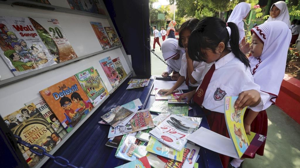 Siswa membaca buku-buku yang tersedia di motor perpustakaan keliling di SDN 02 Malakasari, Jakarta Timur, awal Januari 2019. Layanan perpustakaan keliling ini menjadi sarana yang dinanti para siswa untuk membaca buku-buku baru dan menambah pengetahuan.