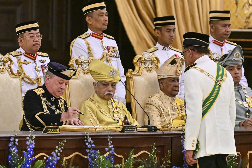 Sultan Ibrahim Sultan Iskandar (depan kiri) menandatangani dokumen yang ia terima dari Perdana Menteri Malaysia Anwar Ibrahim (membelakangi kamera) dalam pengangkatannya sebagai Raja ke-17 Malaysia di Istana Negara di Kuala Lumpur, Malaysia, Rabu (31/1/2024).   