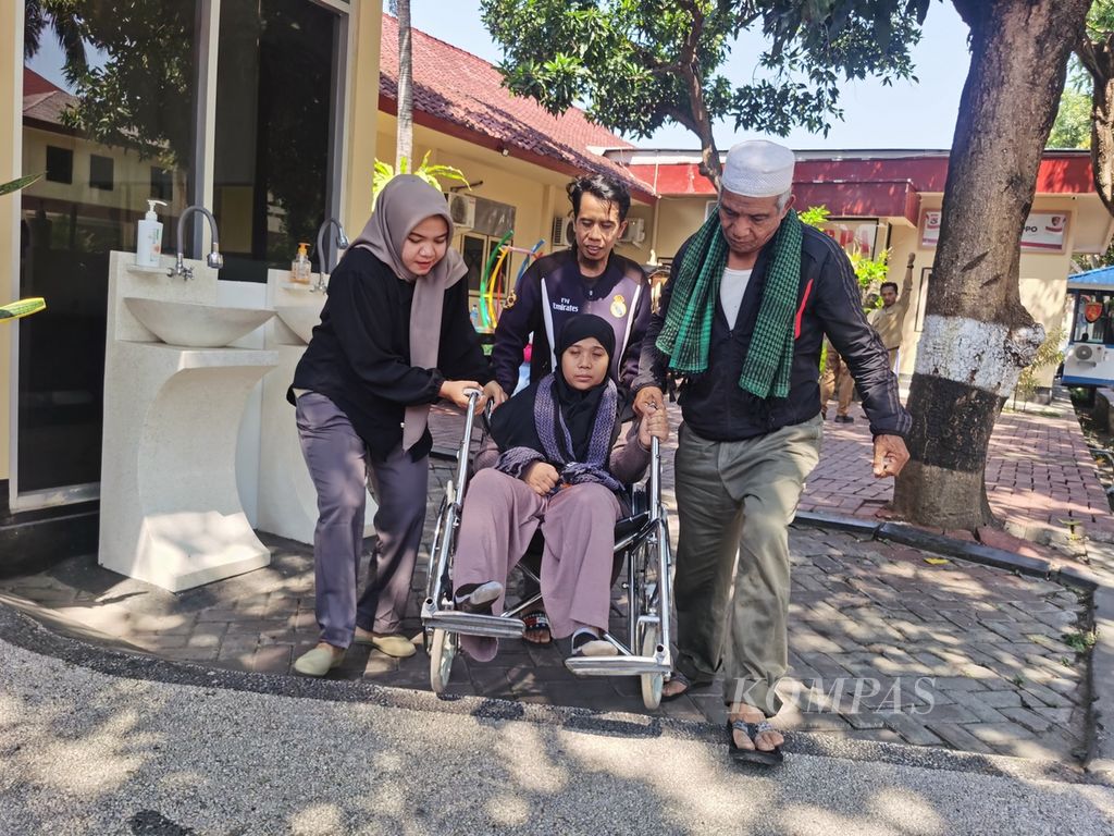 Zul Kipli (tengah) dibantu pendamping dan anggota keluarga mendorong kursi roda yang digunakan istrinya, Budihartini (39), saat tiba di Kantor Direktorat Reserse Kriminal Umum Polda NTB, Senin (25/9/2023). 