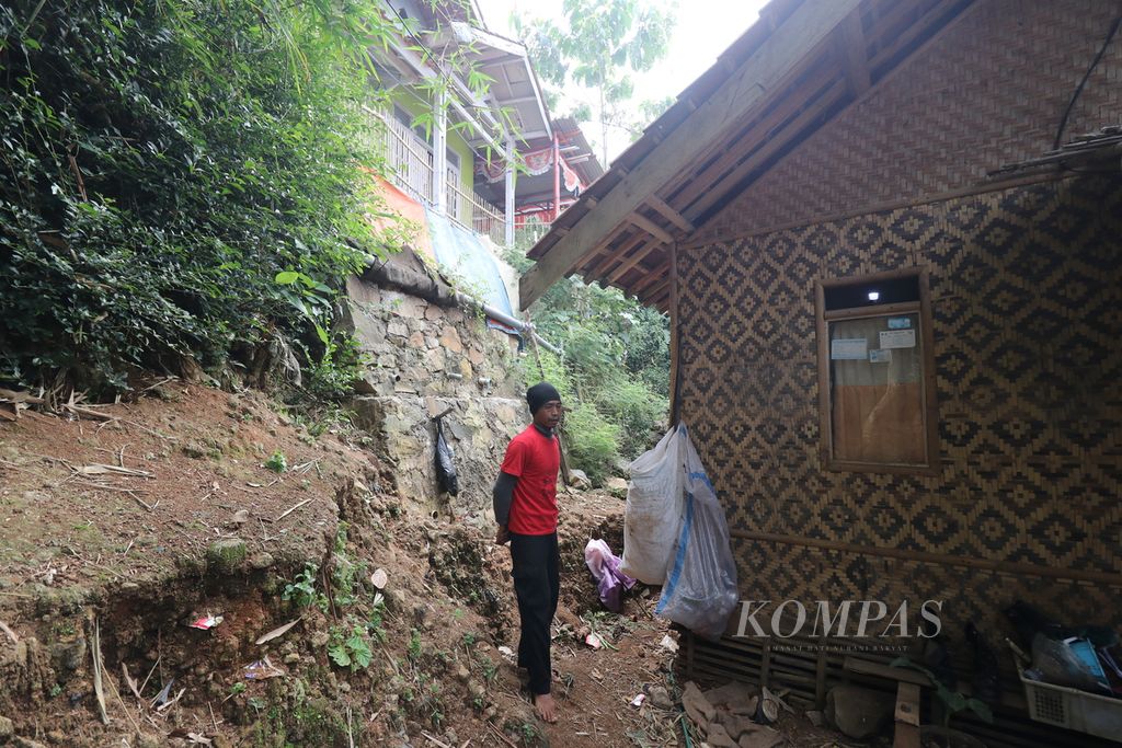 Joli, warga Desa Batulayang, Kecamatan Cililin, Kabupaten Bandung Barat, Jawa Barat, berdiri di samping rumahnya yang terkena longsor, Selasa (7/2/2023).