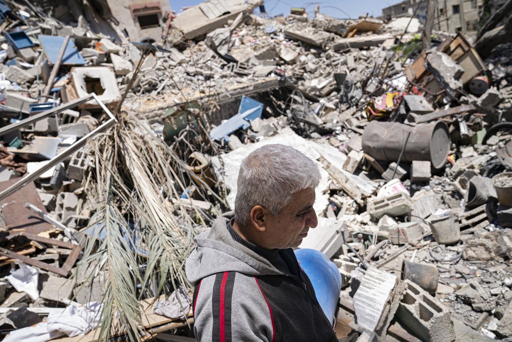 Seorang warga Palestina, Jamaal Herzalla (57), berdiri di dekat puing-puing toko mainan miliknya yang hancur karena serangan udara Israel di Gaza. 