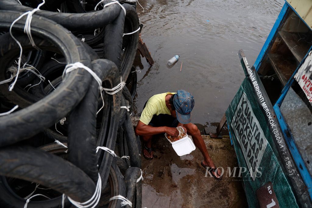 Warga membuka bekal makanannya di tengah banjir yang melanda beberapa kawasan di Pelabuhan Tanjung Emas, Kota Semarang, Jawa Tengah, Jumat (3/2/2023). 