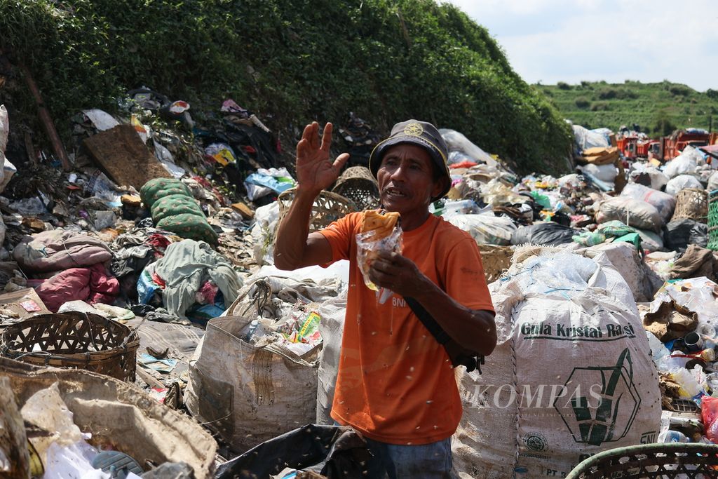 Rohadi (47) makan sebungkus roti sobek yang dia temukan di tumpukan sampah di TPST Bantar gebang, Selasa (26/4/2022). Setiap melihat makanan yang masih terkemas rapi dalam bungkusan dan terlihat layak, Rohadi memakannya sebagai pengobat lapar.