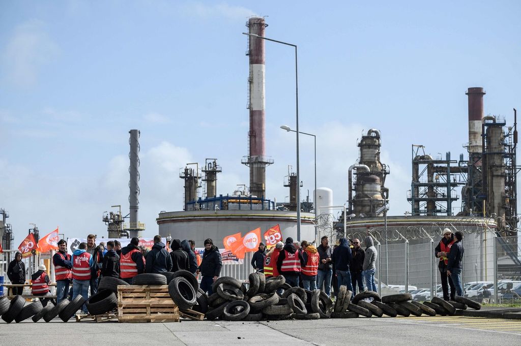 Para pekerja dan anggota serikat pekerja TotalEnergie memblokir jalan masuk menuju kilang Donges dalam aksi unjuk rasa menentang kebijakan pensiun Pemerintah Perancis, Jumat (24/3/2023).